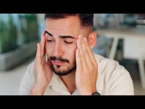 Man with closed eyes touching his temples with both hands